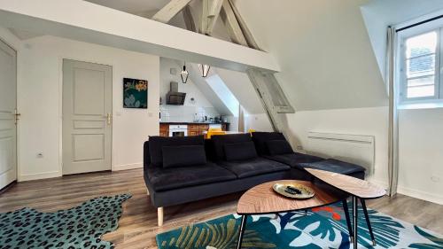 a living room with a black couch and a table at RhizHome - Coeur de ville, appartement spacieux in Auxerre