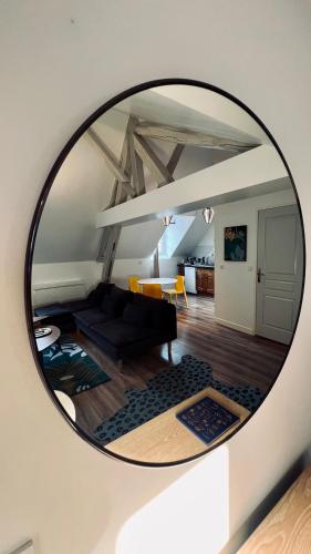 a mirror reflecting a living room with a black couch at RhizHome - Coeur de ville, appartement spacieux in Auxerre