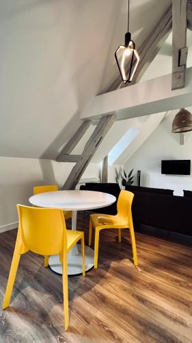 a table and two yellow chairs in a room at RhizHome - Coeur de ville, appartement spacieux in Auxerre