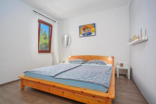 ein Schlafzimmer mit einem Holzbett in einem Zimmer in der Unterkunft Apartments with a parking space Njivice, Krk - 20542 in Njivice