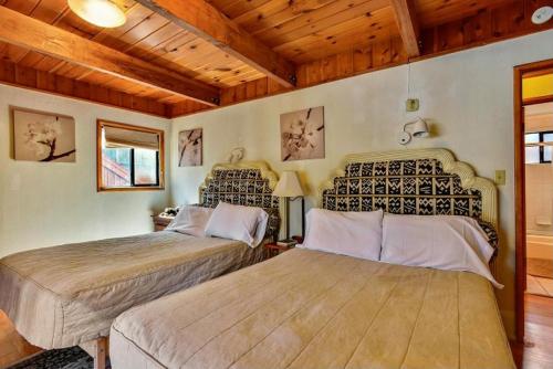 2 bedden in een kamer met houten plafonds bij Summit Escape B - Rustic cabin with a hot tub and barbecue! Wood fireplace! Walk to Slopes! in Big Bear Lake