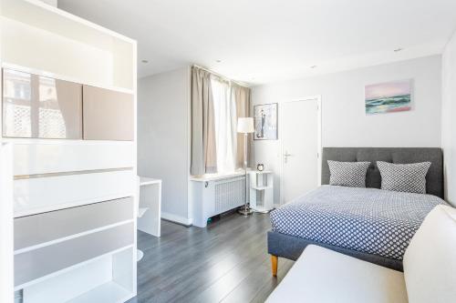 a white bedroom with a bed and a window at Auteuil Cozy Studio in Paris