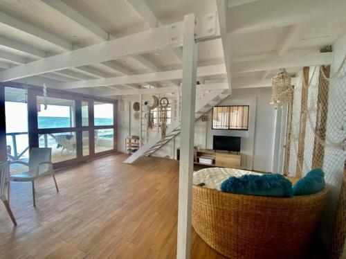 una sala de estar con una escalera y una habitación con una mesa en La Soñadora casa frente al mar con piscina en Canoas