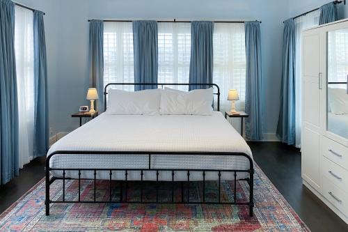 a bed in a bedroom with blue walls and windows at Woodlawn Avenue Beauty in San Antonio
