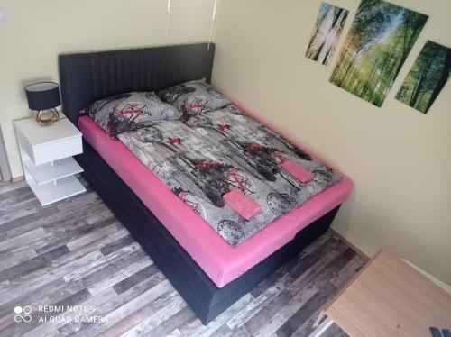a bedroom with a bed with a pink and black comforter at Apartments Lake Bohinj Medja in Bohinj