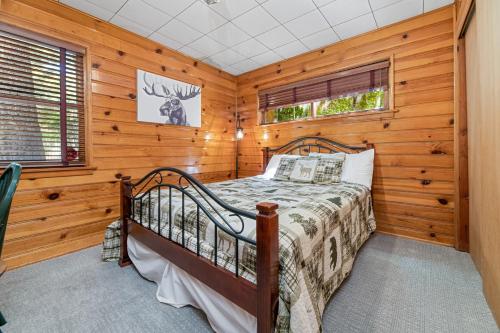 um quarto com uma cama num quarto com paredes de madeira em Stillwater Cove Lakefront - Breathtaking views, charming vintage cabin, woodsy interior! Boat Dock! em Big Bear Lake