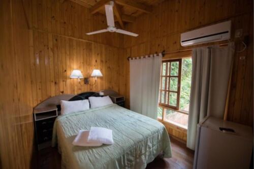 1 dormitorio con 1 cama, ventilador de techo y ventana en Hotel Los Lapachos en Puerto Iguazú