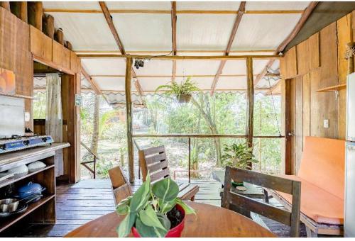 eine Küche mit einem Tisch und Stühlen sowie einem großen Fenster in der Unterkunft Luminosa Uvita Hostel in Uvita