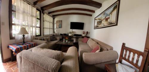 a living room with a couch and chairs and a tv at Villas Santa Ana-Ricardo in Antigua Guatemala