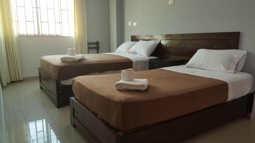 Dos camas en una habitación de hotel con toallas. en HOSTAL ROGGERIO SRL, en Barranca