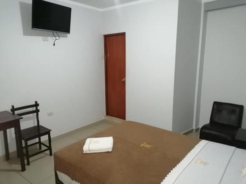 Dormitorio con cama, escritorio y TV en HOSTAL ROGGERIO SRL, en Barranca