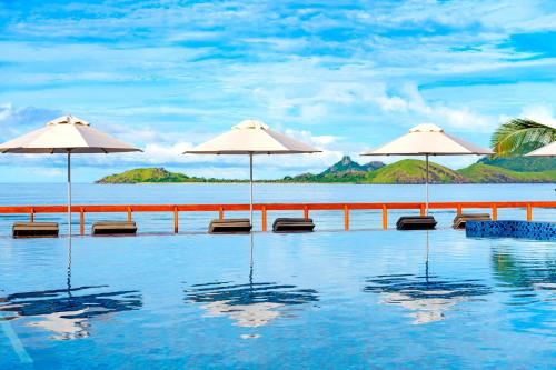 a swimming pool with umbrellas and a view of the ocean at Sheraton Resort & Spa, Tokoriki Island, Fiji in Tokoriki