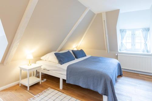 um quarto com uma cama com um cobertor azul e duas janelas em De ole Hüs 1735 em Braderup