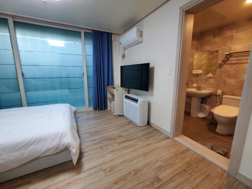 済州市にあるSky Oreum Pensionのベッドルーム1室(ベッド1台付)、バスルーム(テレビ付)