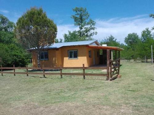 una pequeña casa en un campo con una valla en Cabaña La Agostina en Mina Clavero