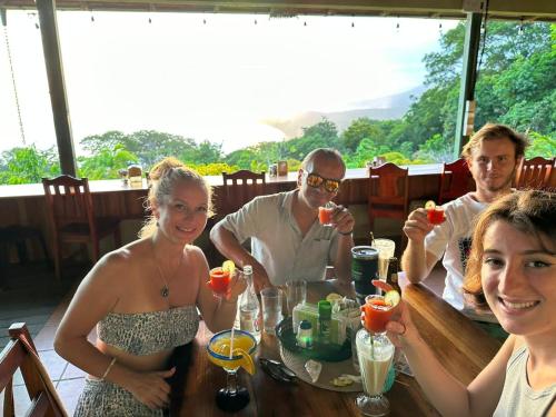 a group of people sitting at a table with drinks at Luminosa Uvita Hostel in Uvita