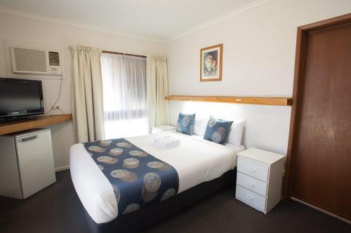 a hotel room with a bed and a television at Majestic Motel in Horsham