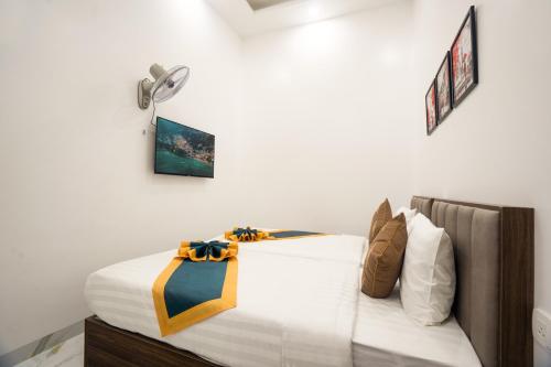 a bedroom with a large white bed with a yellow and black bow on it at BinBin Phúc Dalat Hotel in Da Lat