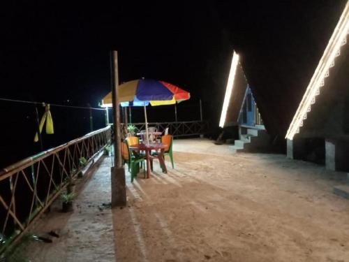 a table with an umbrella on a balcony at night at Newang Gaon Eco Homestay Aaradhya by StayApart in Kalimpong
