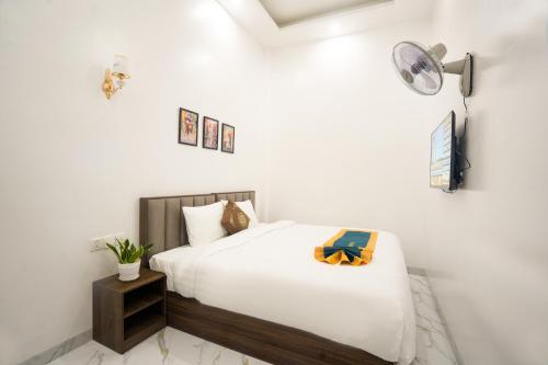 a white bedroom with a bed and a night stand at BinBin Phúc Dalat Hotel in Da Lat