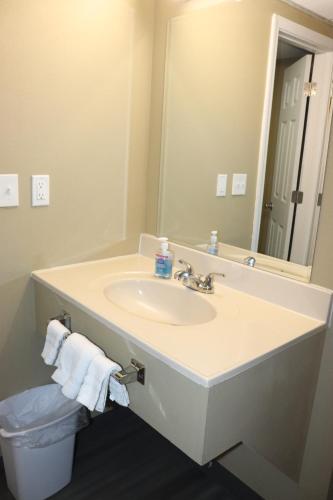 La salle de bains est pourvue d'un lavabo et d'un miroir. dans l'établissement Deluxe Inn Miami OK, à Miami