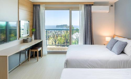 a hotel room with two beds and a view of the ocean at Seogwipo Worldcup Resort in Seogwipo