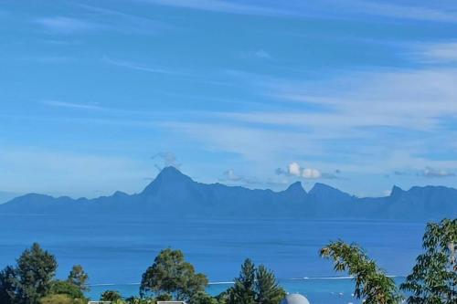a view of the ocean and mountains in the distance at Logement Cosy avec Piscine et Vue Tahiti Punaauia in Punaauia