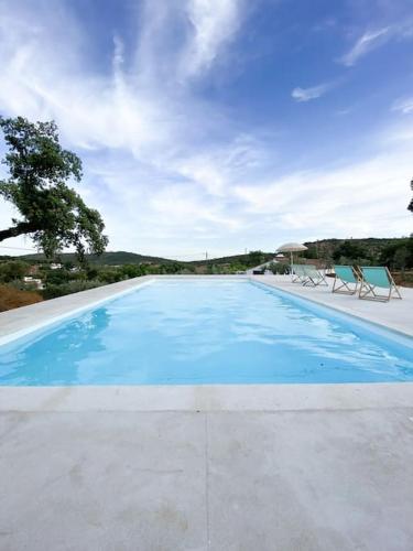 a large blue swimming pool with two lawn chairs at Monte da Borrega - Casa de Campo in Esperança