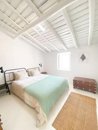 um quarto branco com uma cama e uma mala em Monte da Borrega - Casa de Campo em Esperança