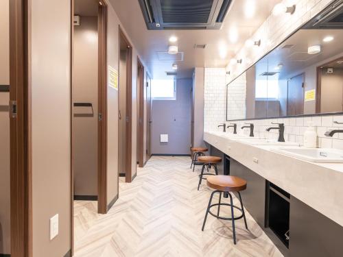 a corridor of a bathroom with two sinks and stools at Tabist MAYUDAMA CABIN in Yokohama