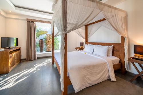 a bedroom with a canopy bed and a television at Villa Alopa Seminyak in Seminyak