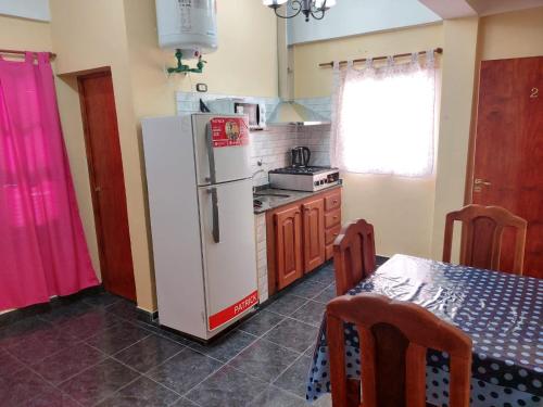 eine Küche mit einem weißen Kühlschrank und einem Tisch in der Unterkunft Hotel y Departamentos Arroyos in Perico