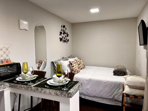 um quarto com uma cama e uma mesa com copos de vinho em Alto da Villa Loft em Ouro Preto