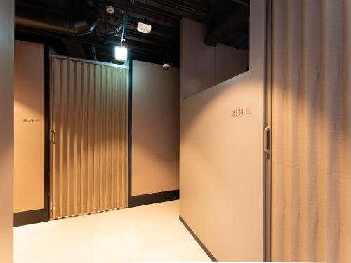 a row of elevators in a room with brown walls at Tabist MAYUDAMA CABIN in Yokohama