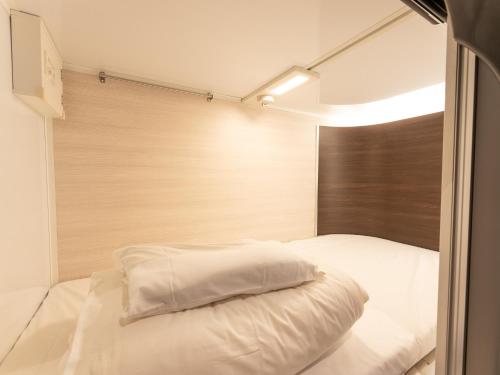 a bedroom with a white bed with a wooden headboard at Tabist MAYUDAMA CABIN in Yokohama