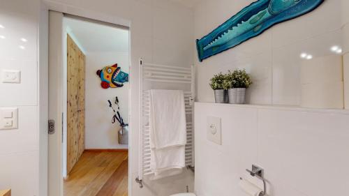 La salle de bains est pourvue de toilettes et d'un poisson bleu sur le mur. dans l'établissement Abitaziun Quadratscha 18 - Samedan, à Samedan