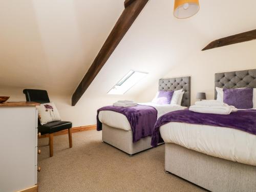 a attic bedroom with two beds and a chair at Wheal Prosper in St Austell
