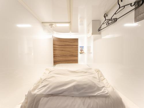 a bedroom with a white bed in a white room at Tabist MAYUDAMA CABIN in Yokohama