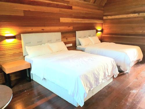 two beds in a room with wooden walls at 仙本那中梁度假庄园 ZhongLiang Holiday Garden Semporna in Semporna