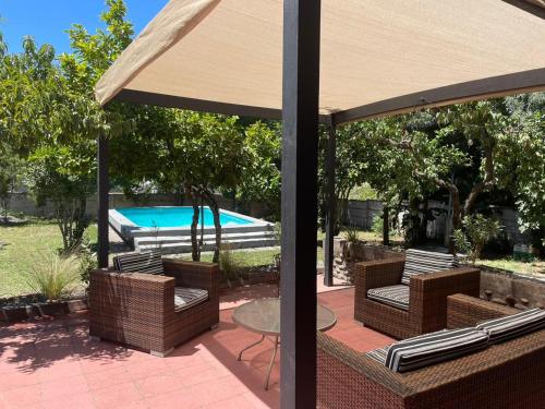 a patio with a table and chairs and a pool at Agradable casa con Tina de agua Caliente y Piscina in Quillón