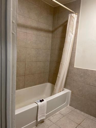 La salle de bains est pourvue d'une baignoire blanche et d'une douche. dans l'établissement Pennswoods Inn, à Manheim