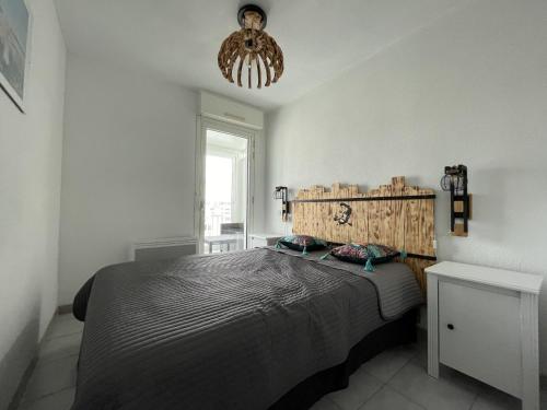une chambre avec un lit et un lustre dans l'établissement 2 pièces mezzanine, parking privé, animaux admis - FR-1-338-475, à Sète