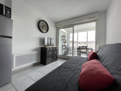 une chambre avec un lit et une télévision et un balcon dans l'établissement 2 pièces mezzanine, parking privé, animaux admis - FR-1-338-475, à Sète