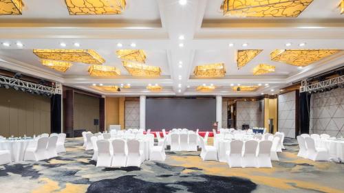 a banquet hall with white chairs and a projection screen at Holiday Inn Shijiazhuang Central by IHG in Shijiazhuang