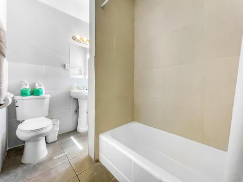 a white bathroom with a toilet and a bath tub at The Palms in Hollywood