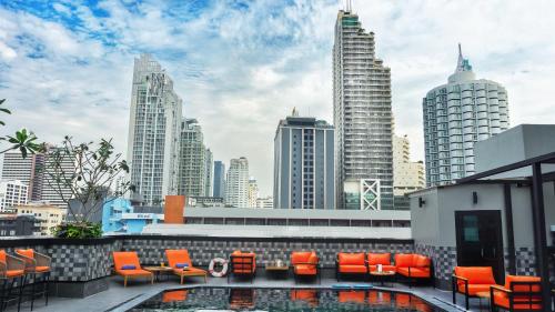 um pátio no último piso com cadeiras laranja e vista para a cidade em Ramada by Wyndham Bangkok Sukhumvit 11 em Bangkok