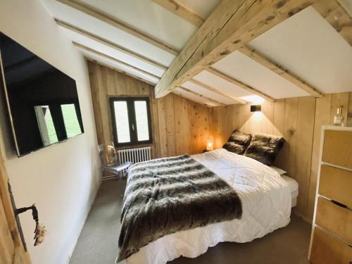 a bedroom with a large bed in a room with wooden walls at Chalet pour 10 pers. avec cheminée et bain norvégien - FR-1-733-70 in Crest-Voland