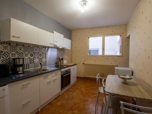 une cuisine avec des armoires blanches, une table et une fenêtre dans l'établissement Élégant 3 pièces avec balcon, centre de Périgueux, proche cathédrale et marché - FR-1-616-326, à Périgueux