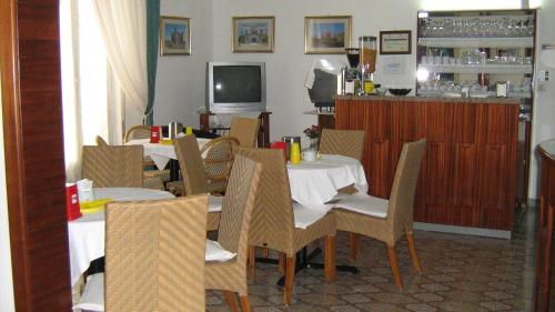 a dining room with tables and chairs and a television at Albergo Europa in Marina di Mancaversa