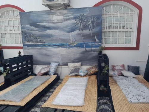 Habitación con 3 camas y una pintura en la pared. en "LE CHAT QUI PECHE" Hostel a 150 metros da PRAIA de PAJUCARA, en Maceió